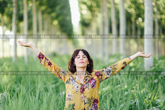 Enjoying the nature. Young woman arms raised enjoying the fresh air in green forest. Female with eyes closed.. Woman arms raised enjoying the fresh air in green forest. Стоковое фото, агентство Ingram Publishing / Фотобанк Лори