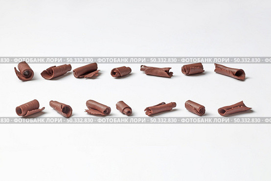 Even lines of arranged shavings of organic dark chocolate in rows on white background. Row of raw chocolate shavings. Стоковое фото, агентство Ingram Publishing / Фотобанк Лори