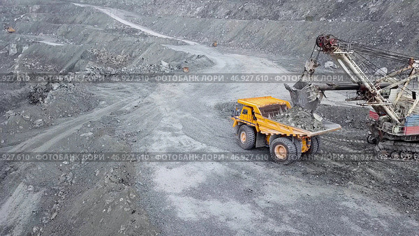 Excavator falls asleep rubble in dumper on outdoor quarry in extraction of minerals. Стоковое фото, фотограф David Kashakhi / Фотобанк Лори