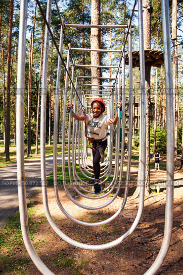 Exploring the Heights in a Thrilling Rope Park Adventure Among Towering Trees and Sunshine. Редакционное фото, фотограф Aleksandr Golubev / Фотобанк Лори