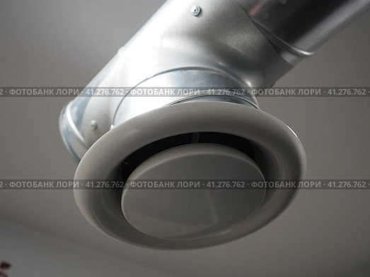 Extractor hood in a public toilet. Round metal pipe with gray air extractor. Engineering ventilation systems. Galvanized pipes under the ceiling of the room. Plastic round tip. Стоковое фото, фотограф Юлия Петровская / Фотобанк Лори