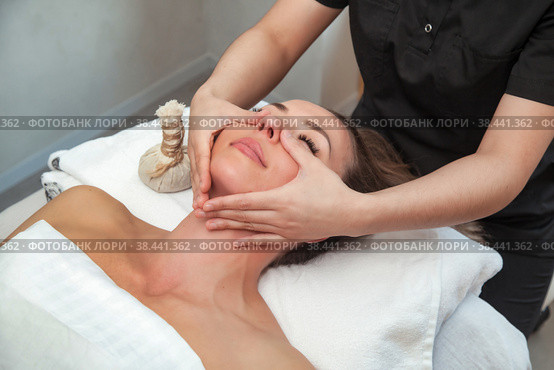 Facial massage woman in SPA salon. Massaging therapist makes face therapy massage for female. Sensual healthy massaging in hands of professional masseur. Concept of health care and beauty. Copy space. Стоковое фото, фотограф Aleksandr Golubev / Фотобанк Лори