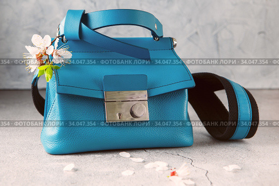 fashionable turquoise Crossbody bag on the gray concrete background. Blue crossbody bag made of sheepskin and cowhide leather, a metal clasp, shoulder. Стоковое фото, фотограф Nataliia Zhekova / Фотобанк Лори