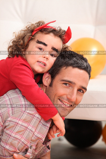 Father giving dressed as devil a piggy-back. Стоковое фото, агентство Ingram Publishing / Фотобанк Лори