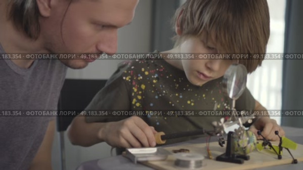 Father teaching his little son to solder electronic contacts at home. Стоковое видео, видеограф Скоробогатова Е. / Фотобанк Лори