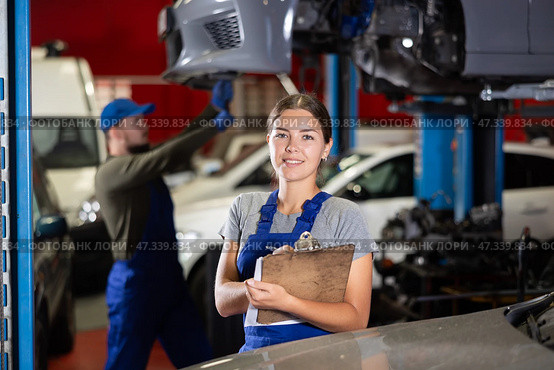 Female car service worker keeps records of work performed by auto mechanics in car service station - makes notes on paper. Стоковое фото, фотограф Яков Филимонов / Фотобанк Лори