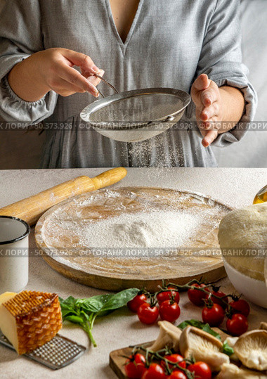 female cook sieving flour wooden board rolling pizza dough. Стоковое фото, агентство Ingram Publishing / Фотобанк Лори