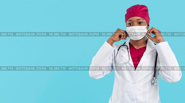 female doctor adjusting her surgeon mask. Стоковое фото, агентство Ingram Publishing / Фотобанк Лори