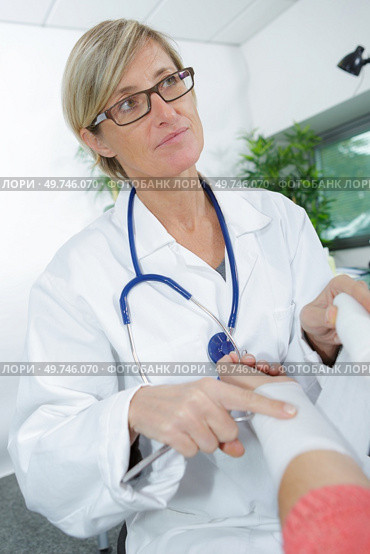 female doctor bandaging male hand sprained wrist. Стоковое фото, агентство Ingram Publishing / Фотобанк Лори