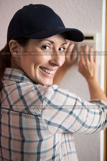 female electrician installing a intercom. Стоковое фото, агентство Ingram Publishing / Фотобанк Лори