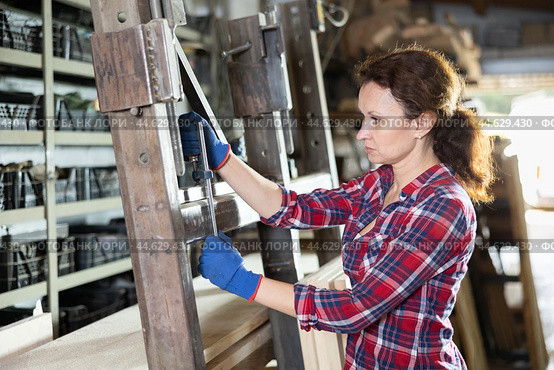 Female employee of workshop stands next to iron rails of workpieces, measures length. Стоковое фото, фотограф Яков Филимонов / Фотобанк Лори