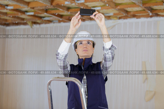 female engineer in a protective helmet taking a picture. Стоковое фото, агентство Ingram Publishing / Фотобанк Лори
