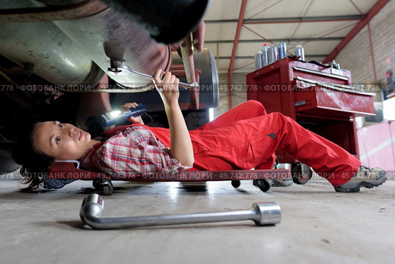 female mechanic underneath a car. Стоковое фото, агентство Ingram Publishing / Фотобанк Лори