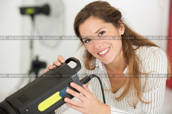 female photographer adjusting flash strobe. Стоковое фото, агентство Ingram Publishing / Фотобанк Лори