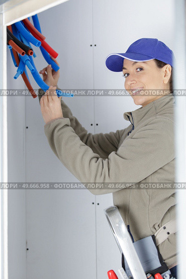 female plumber inspecting bundle of new pipework. Стоковое фото, агентство Ingram Publishing / Фотобанк Лори