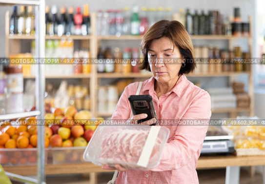 Female purchaser scanning QR code or barcode of pork fillet in shop. Стоковое фото, фотограф Яков Филимонов / Фотобанк Лори