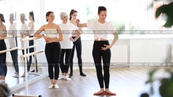 Female teacher leading ballet class, showing graceful dance movements for women of different ages standing at barre, emphasizing discipline in studio. Стоковое видео, видеограф Яков Филимонов / Фотобанк Лори