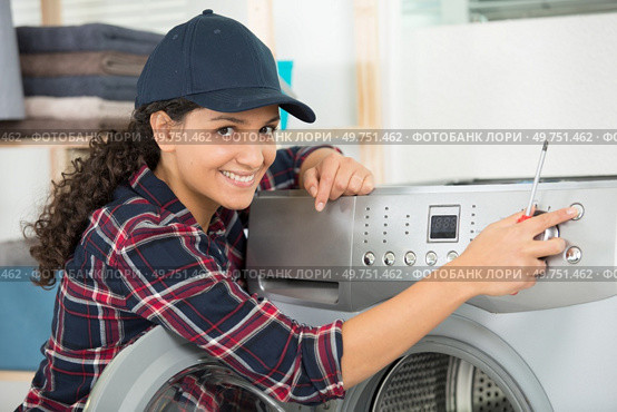female technician fixes a washing machine leak in the kitchen. Стоковое фото, агентство Ingram Publishing / Фотобанк Лори