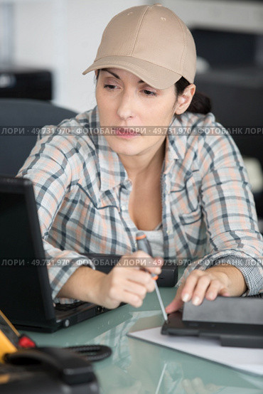female technician working on appliance at her desk. Стоковое фото, агентство Ingram Publishing / Фотобанк Лори