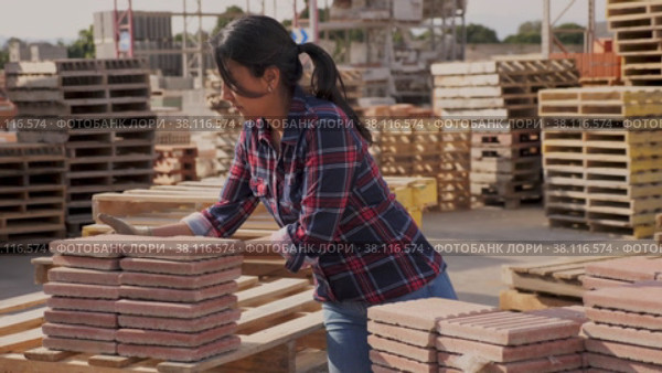 Female worker in gloves sorting red paving slabs in warehouse of building materials. Стоковое видео, видеограф Яков Филимонов / Фотобанк Лори