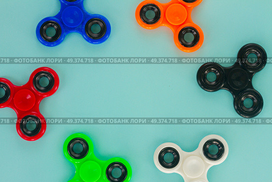 fidget spinners frame on blue background with copy space, popular relaxing toy, generic design. fidget spinner, popular relaxing toy, generic design. Стоковое фото, агентство Ingram Publishing / Фотобанк Лори