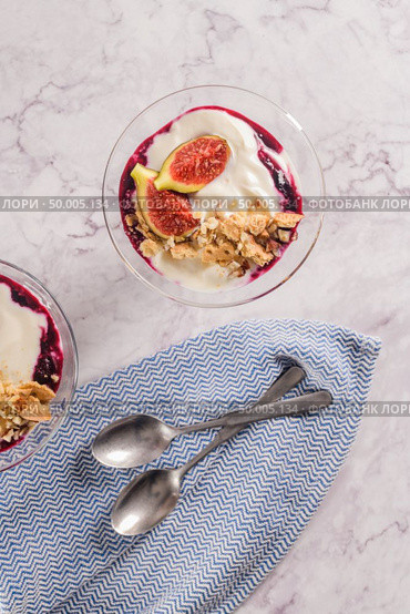 Figs pudding parfait with yogurt, blueberry jam, figs, hazelnut, and cookies in glass on white marble background. Flatlay top view. Стоковое фото, агентство Ingram Publishing / Фотобанк Лори