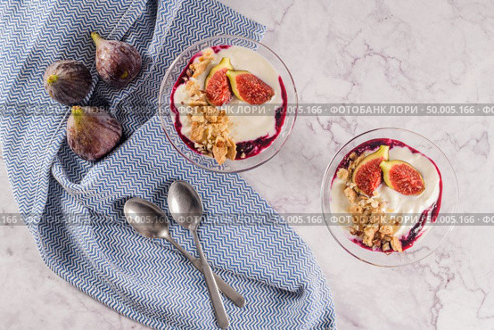 Figs pudding parfait with yogurt, blueberry jam, figs, hazelnut, and cookies in glass on white marble background. Flatlay top view. Стоковое фото, агентство Ingram Publishing / Фотобанк Лори