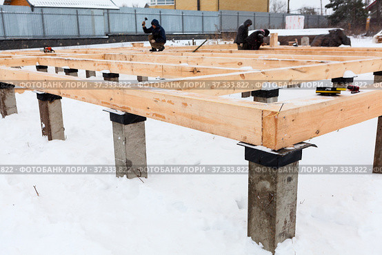 First stage of erection of wooden frame house, housebuilders working with timber in winter season. Стоковое фото, фотограф Кекяляйнен Андрей / Фотобанк Лори