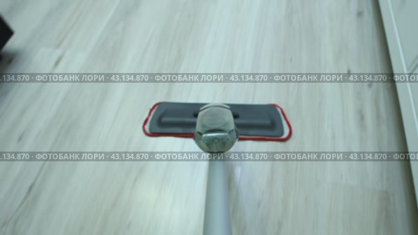 Flat mop with spray and microfiber pad is used for wet cleaning in living room. Стоковое видео, видеограф Владимир Григорьев / Фотобанк Лори