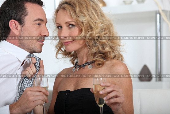 Flirtatious couple drinking champagne at home. Стоковое фото, агентство Ingram Publishing / Фотобанк Лори