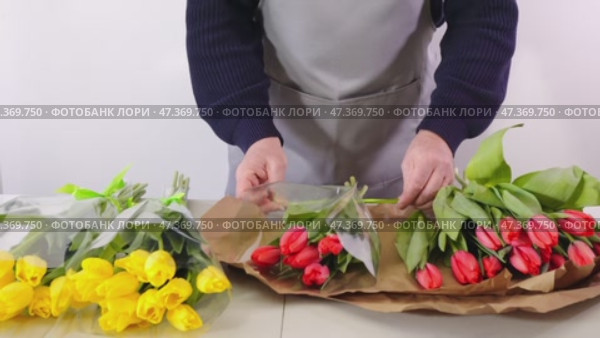 Florist arranging tulip bouquets with careful precision and creative flair. Стоковое видео, видеограф Zakharova Natasha / Фотобанк Лори
