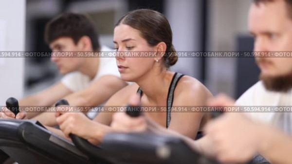 Focused girl works out with stationary bicycle during class at fitness club. Стоковое видео, видеограф Яков Филимонов / Фотобанк Лори