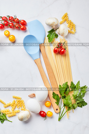 Food background with place for text, with different kinds of pasta, tomatoes, herbs, mushrooms, eggs, seasonings scattered on light marble background, top view. Стоковое фото, фотограф Ирина Буракова / Фотобанк Лори