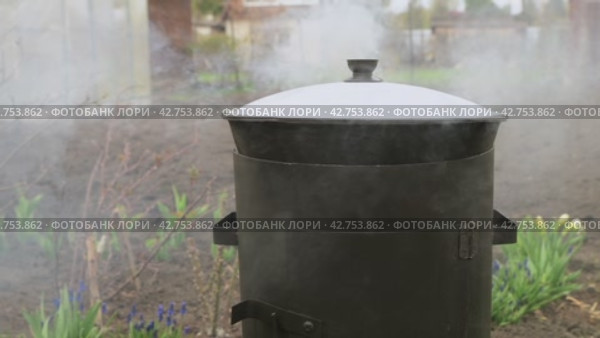 Food is cooked in a cauldron outdoors in the yard. Steam from boiling water. Стоковое видео, видеограф Дмитрий Кобзев / Фотобанк Лори