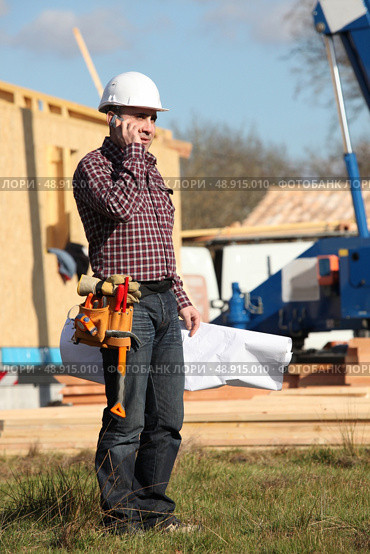Foreman stood by wooden house. Стоковое фото, агентство Ingram Publishing / Фотобанк Лори