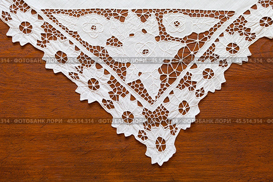 Fragment of beautiful corner white napkin with lace patterns embroidered in richelieu style or cutwork embroidery on wooden table. Vintage handicraft for home decoration. Copy space, flat lay, close-up. Стоковое фото, фотограф Виктория Катьянова / Фотобанк Лори