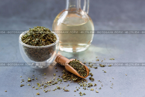 Fragrant spices. Dried parsley and a bottle of oil on a gray background. Free space. Стоковое фото, фотограф Photojuli / Фотобанк Лори