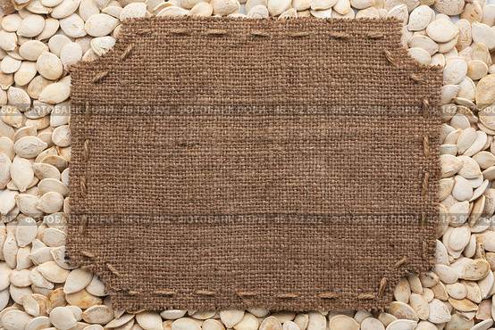 Frame made of burlap with stitches and place for your text lying on pumpkin seeds. Стоковое фото, фотограф Александр Собко / Фотобанк Лори