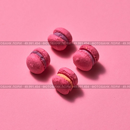 Fresh baked purple pink macaroon pastry cookies in pink background, top view. Sweets. Food background.. pink macaroons on pink background, homemade food. Стоковое фото, агентство Ingram Publishing / Фотобанк Лори