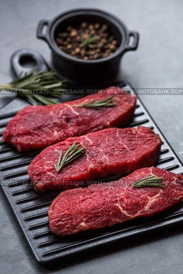 Fresh meat. Raw beef steaks with rosemary and spices on a stylish blackboard. Flat top view. Стоковое фото, фотограф Photojuli / Фотобанк Лори