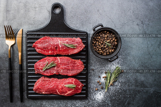 Fresh meat. Raw beef steaks with rosemary and spices on a stylish blackboard. Flat top view. Стоковое фото, фотограф Photojuli / Фотобанк Лори