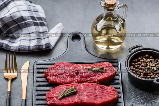 Fresh meat. Raw beef steaks with rosemary and spices on a stylish blackboard. Flat top view. Стоковое фото, фотограф Photojuli / Фотобанк Лори