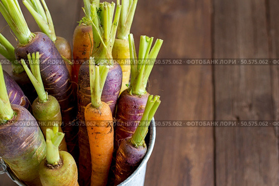 Fresh organic rainbow carrots in a bucket on a wooden table. Стоковое фото, агентство Ingram Publishing / Фотобанк Лори