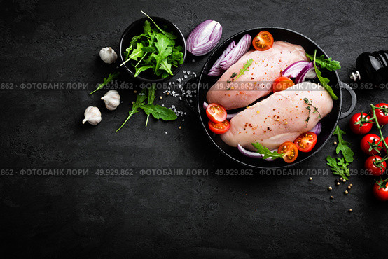 Fresh raw chicken meat, fillet marinated with spices, onion and tomatoes on black background. Top view. Стоковое фото, агентство Ingram Publishing / Фотобанк Лори
