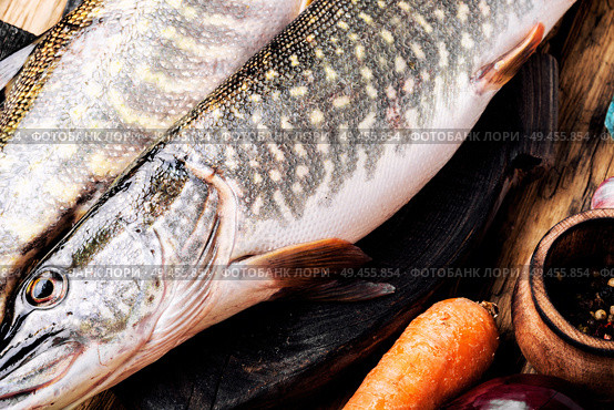 Fresh raw fish on wooden cutting board.Raw fish with spices for cooking.. Fish pike on the kitchen board. Стоковое фото, агентство Ingram Publishing / Фотобанк Лори