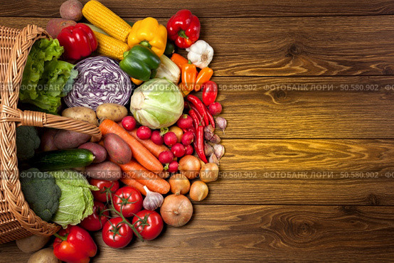 Fresh vegetables next to the overturned basket on the wooden surface. Стоковое фото, агентство Ingram Publishing / Фотобанк Лори