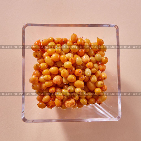 Freshly picked natural orange berries sea buckthorn in plate on paper background. Concept of healthy organic colorful food.. Natural organic sea buckthorn in the glass plate - yellow ripe sweet berries on a beige paper background. Top view. Стоковое фото, агентство Ingram Publishing / Фотобанк Лори