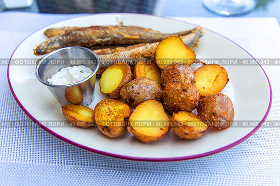 Fried smelt with boiled potatoes and mushroom sauce on a white plate. Delicious rustic lunch. Стоковое фото, фотограф Евгений Ткачёв / Фотобанк Лори