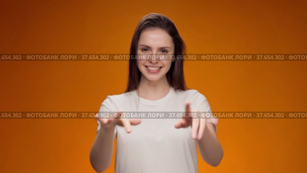 Friendly young woman communicating with deaf-mute sign language against yellow background. Стоковое видео, видеограф Сергей Толмачёв / Фотобанк Лори
