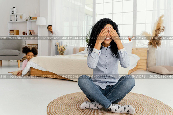 front view smiley mother playing hide seek with her children home. Стоковое фото, агентство Ingram Publishing / Фотобанк Лори